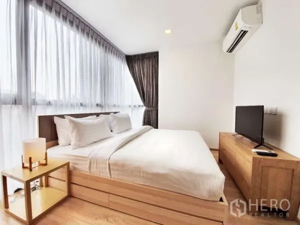 公寓 出售在Watthana, Bangkok - 主卧配大床、转角大窗、空调与木质家具。