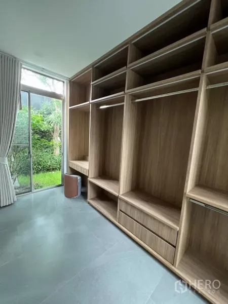 Detached House for rent in Saphan Sung, Bangkok - Walk-in closet with full-height wooden cabinetry and a garden view through sliding glass doors.