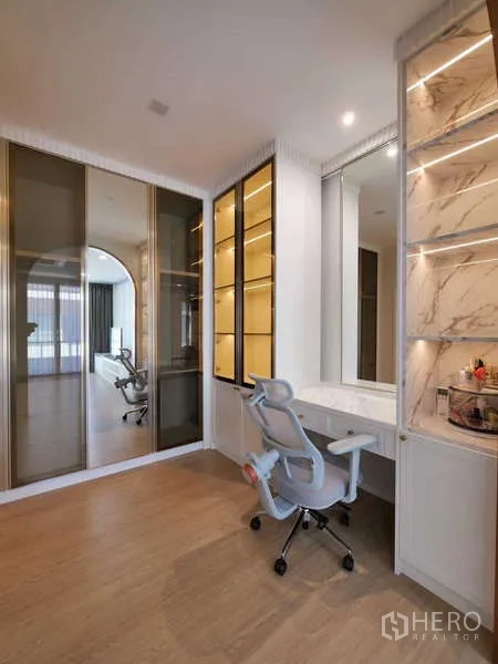 Detached House for rent or sale in Thanyaburi, Pathum Thani - Built-in study or dressing area with glass-door wardrobes, illuminated shelving and a work desk.