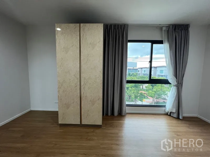 Detached House for rent in Saphan Sung, Bangkok - Bedroom with wide window, freestanding wardrobe and greenery view.