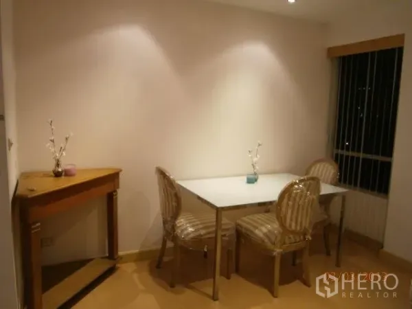 Condominium for rent in Khlong Toei, Bangkok - Cozy dining nook with a glass-top table, striped chairs, console table, and window blinds.