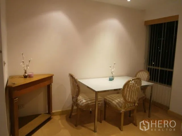 Condominium for rent in Khlong Toei, Bangkok - Cozy dining nook with a glass-top table, striped chairs, console table, and window blinds.