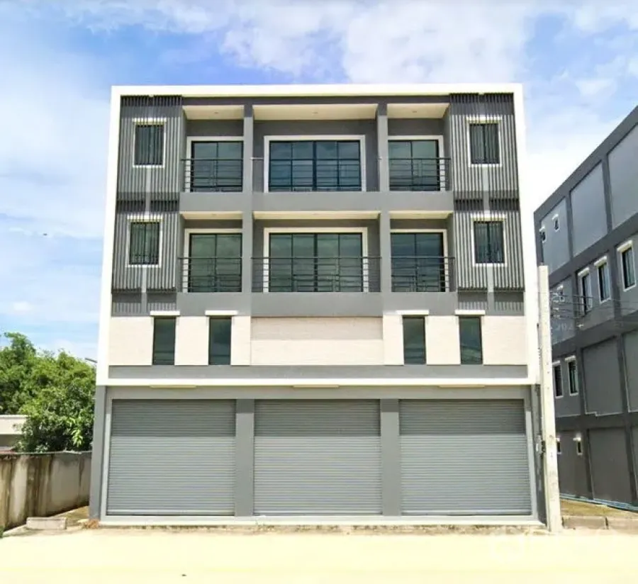 货栈 出租或出售在Nong Chok, Bangkok - 现代三层商业建筑外立面，带阳台与多樘卷闸门。