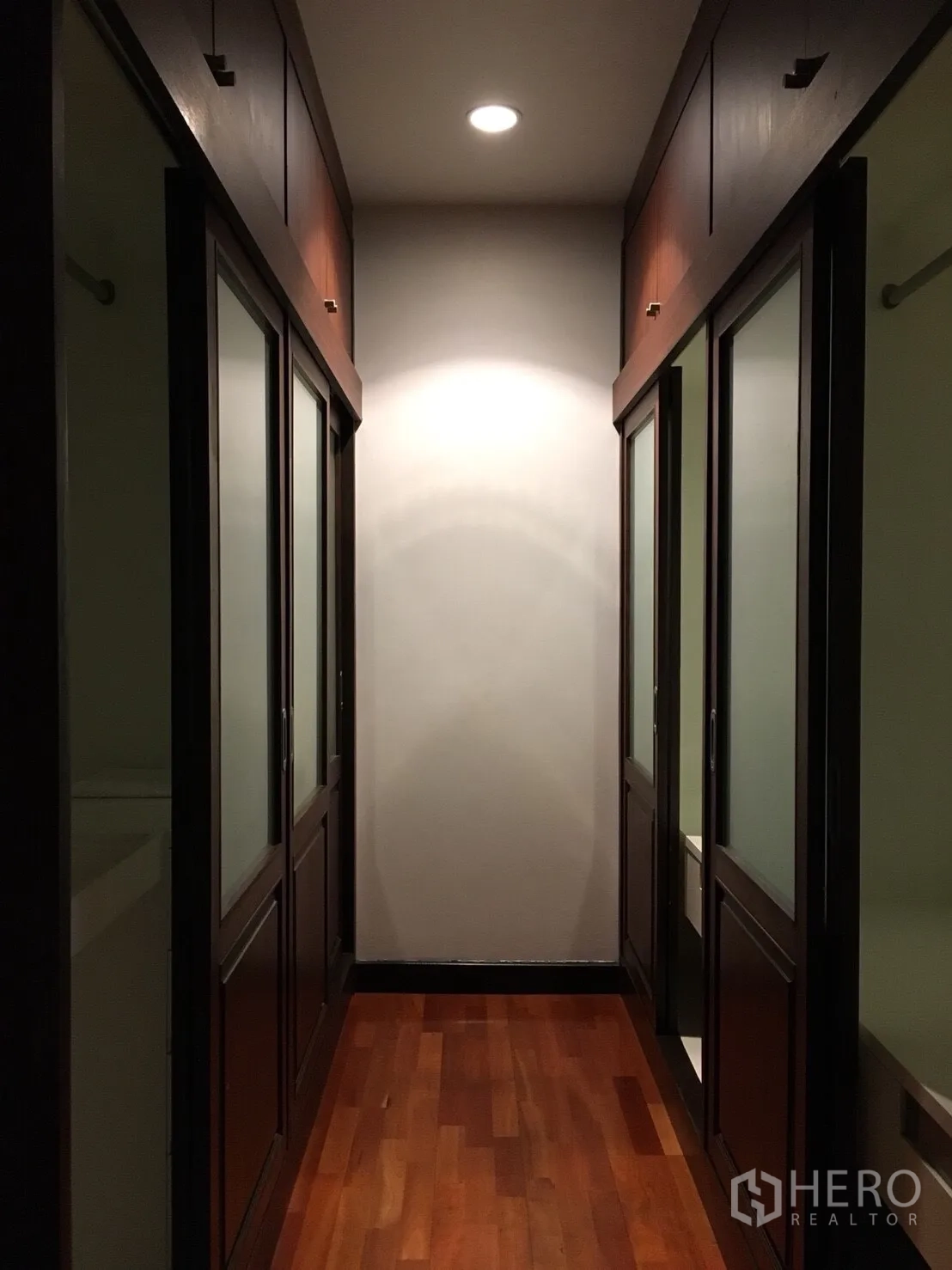 公寓 出租在Watthana, Bangkok - 步入式衣帽间走道，滑门衣柜、筒灯与木地板。