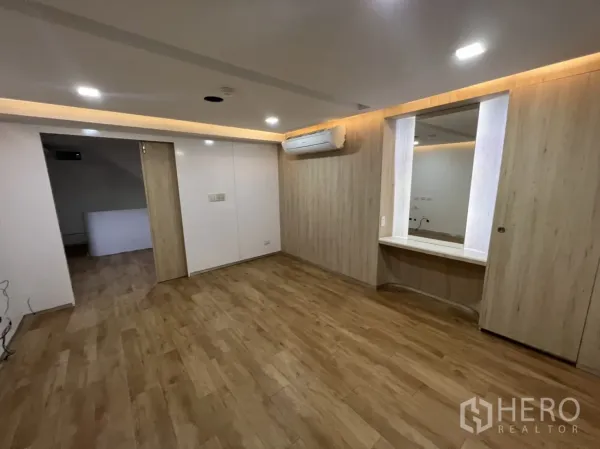 Shophouse for rent or sale in Watthana, Bangkok - Renovated room with wood-look flooring, built-in vanity and a split-type air conditioner.