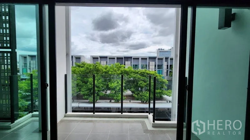 Home Office for rent - Balcony with glass railing facing neighboring buildings and trees.