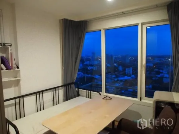 Condominium for rent in Khlong Toei, Bangkok - Bright room with daybed and large windows showcasing night city views.