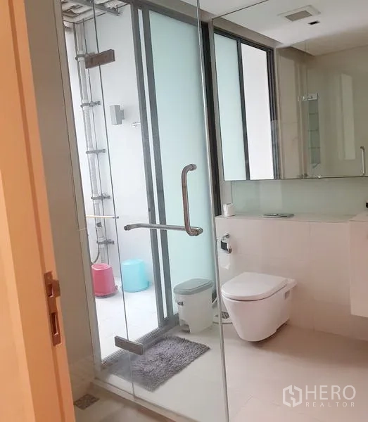公寓 出租在Khlong Toei, Bangkok - 现代浴室，玻璃淋浴间与壁挂式马桶，磨砂窗确保私密。