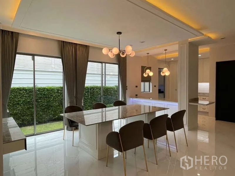 Detached House for rent or sale in Lat Krabang, Bangkok - Dining area with a marble-top table, six chairs and sliding doors to the garden.