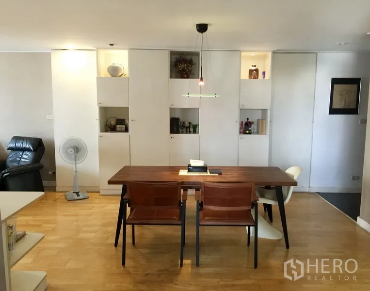 Condominium for rent or sale in Watthana, Bangkok - Bright dining area with wooden table and built‑in white cabinets with display niches in a Bangkok condo.
