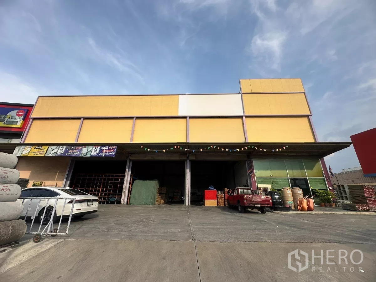 Warehouse for rent in Mueang Nonthaburi, Nonthaburi - Front facade of the yellow warehouse showing three loading bays beneath a canopy with easy vehicle access.