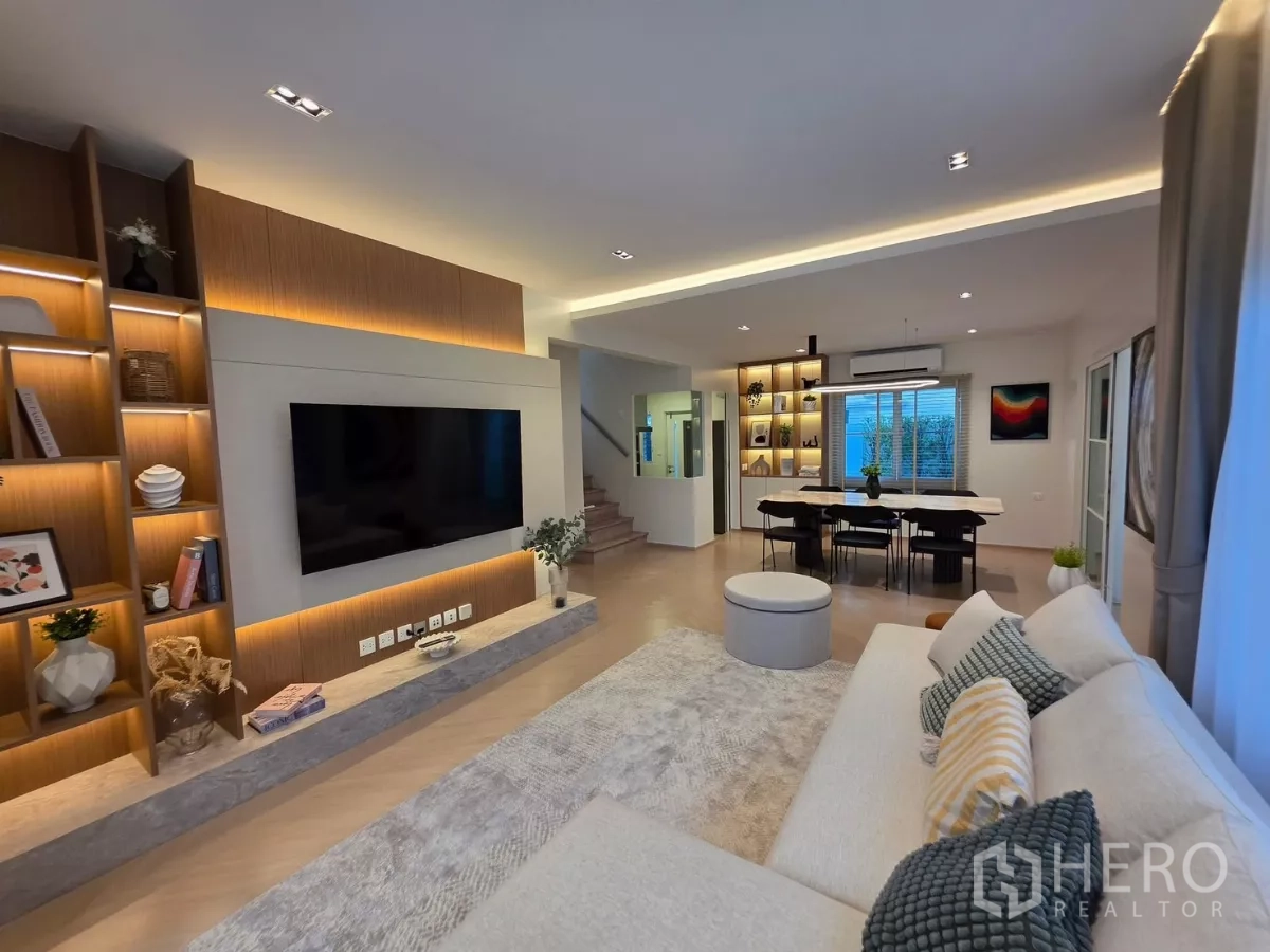 Detached House for rent in Bang Phli, Samut Prakan - Spacious lounge with big TV, display shelves and dining space beside the staircase.