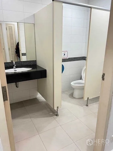 Office Space for rent in Wang Thonglang, Bangkok - Restroom area with partitioned stalls, a countertop basin, and easy-clean tiles.