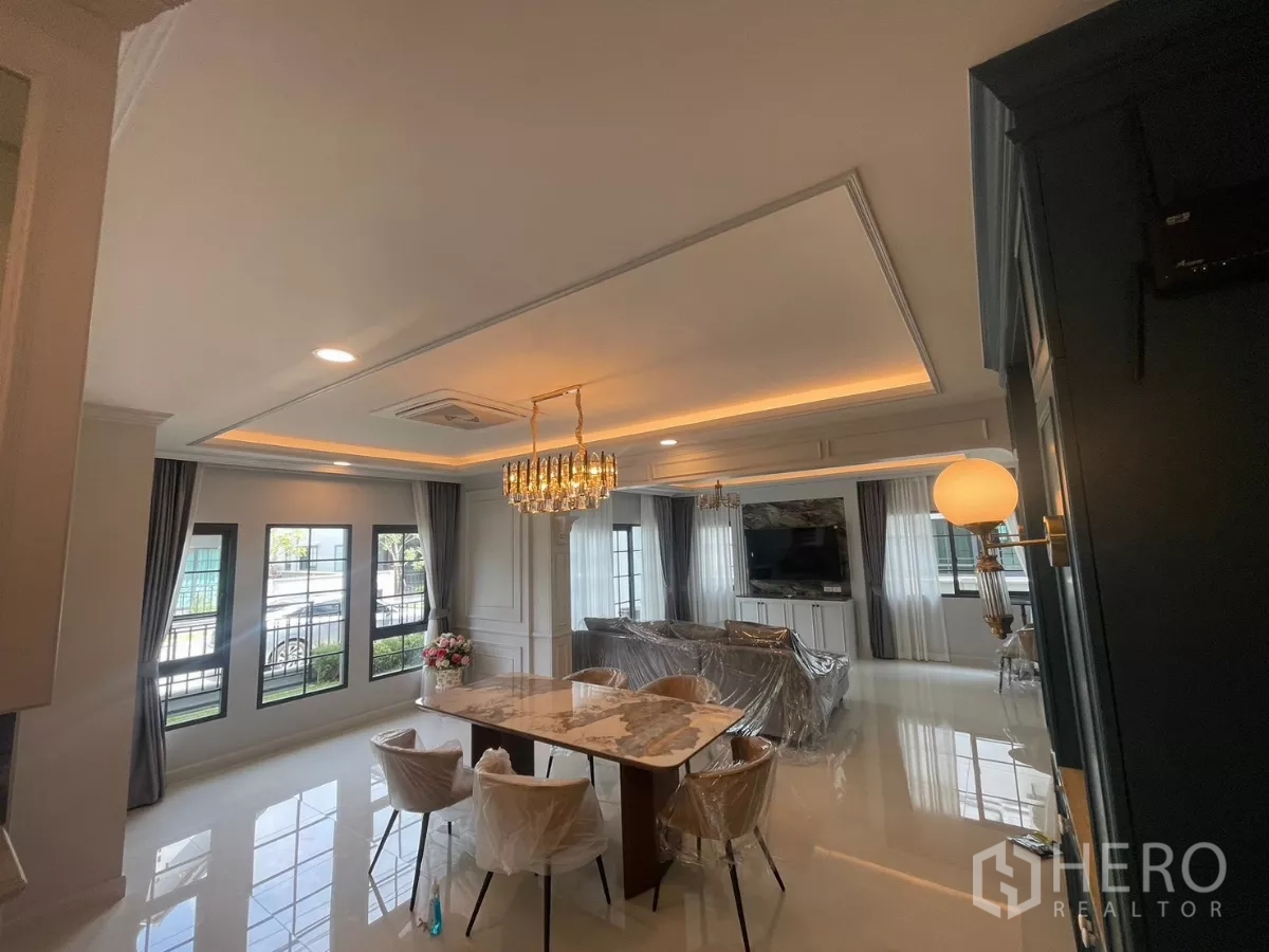 Detached House for rent in Bang Phli, Samut Prakan - Open-plan dining and living area with marble table, chandelier and large windows.