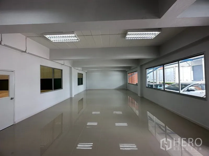 Factory for rent in Bang Phli, Samut Prakan - Bright office floor with large windows and glossy tile finish overlooking parking.