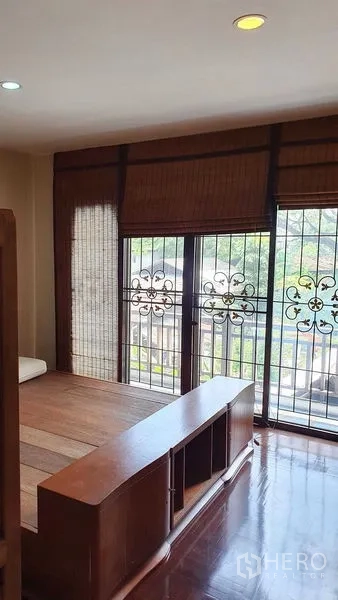 Townhouse for rent or sale in Suan Luang, Bangkok - Upper-floor room with wide windows, wrought-iron grilles and bamboo blinds.