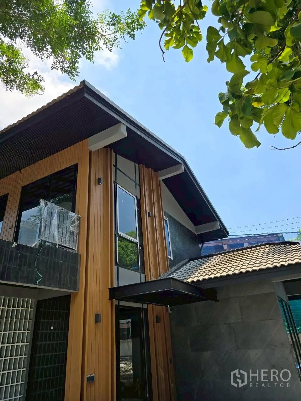 独栋房屋 for rent in Phra Khanong, Bangkok - 现代两层住宅外立面，木纹饰面与高窗。