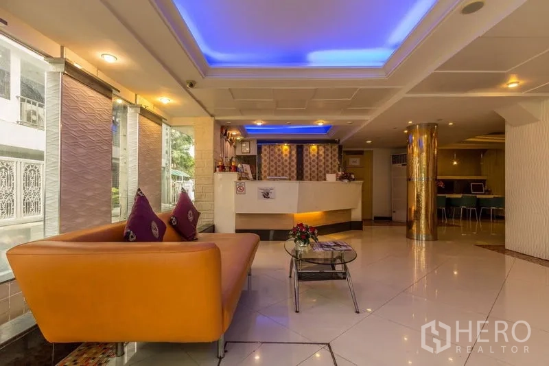 Retail Space for rent - Reception lounge with an orange sofa, feature lighting and street-facing windows.