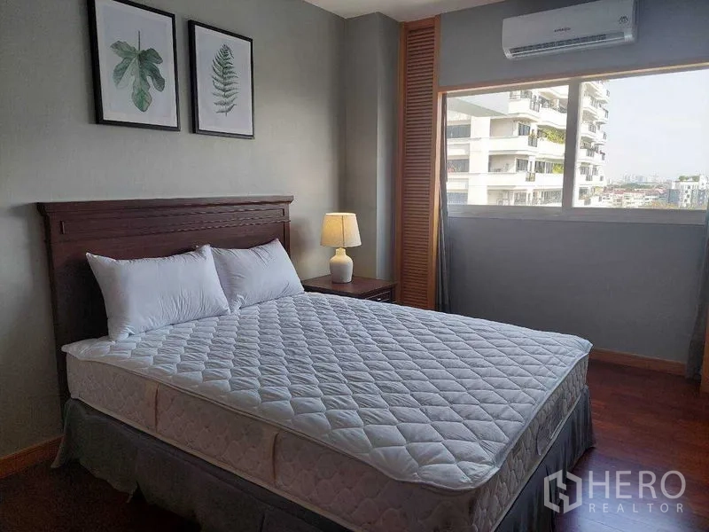 Apartment for rent - Bedroom with city-view window, queen bed, bedside lamp, air conditioner and wooden floors.