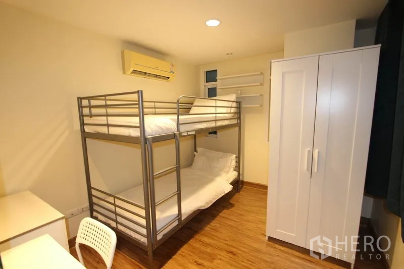 Condominium for rent or sale in Wang Thonglang, Bangkok - Guest bedroom with metal bunk bed, white wardrobe, study desk, and air conditioning.