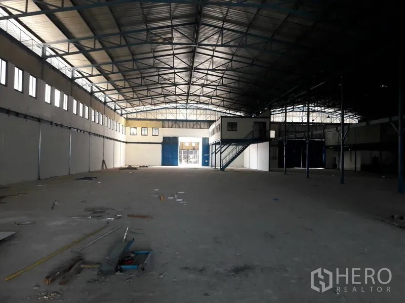 货栈 出租在Mueang Samut Prakan, Samut Prakan - 开放式仓库，前方蓝色装卸大门、侧墙高窗与夹层办公室