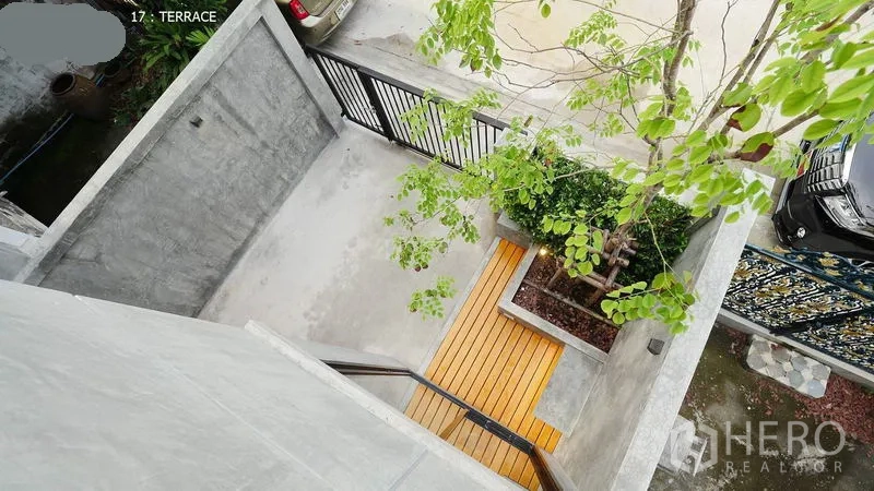 Townhouse for rent in Huai Khwang, Bangkok - Aerial view of gated carport and front terrace with tree and wooden deck.