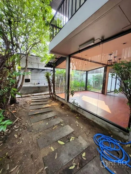 Home Office for rent in Lat Phrao, Bangkok - Garden path beside a glass-walled room with stepping stones and leafy plants along the side yard.
