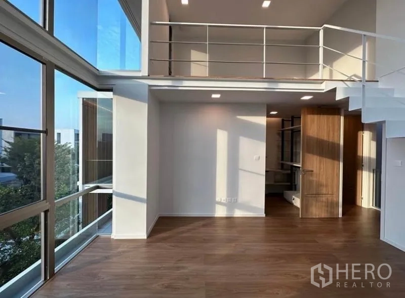Detached House for rent - Double-height room with mezzanine, floor-to-ceiling corner windows and wood flooring.