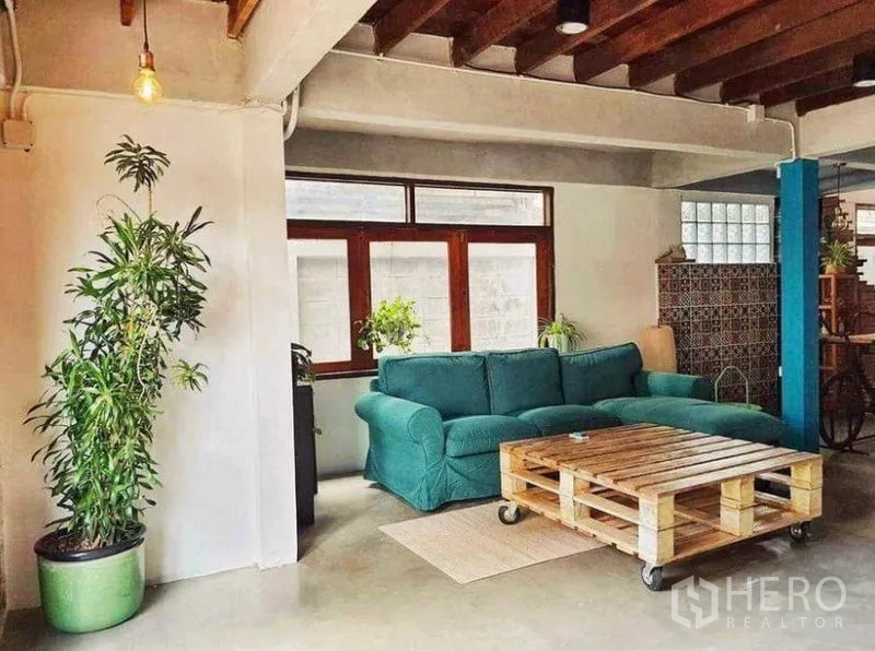 独立式住宅 出租在Pathum Wan, Bangkok - 阁楼风客厅，青绿色沙发，托盘茶几，外露梁木与大窗