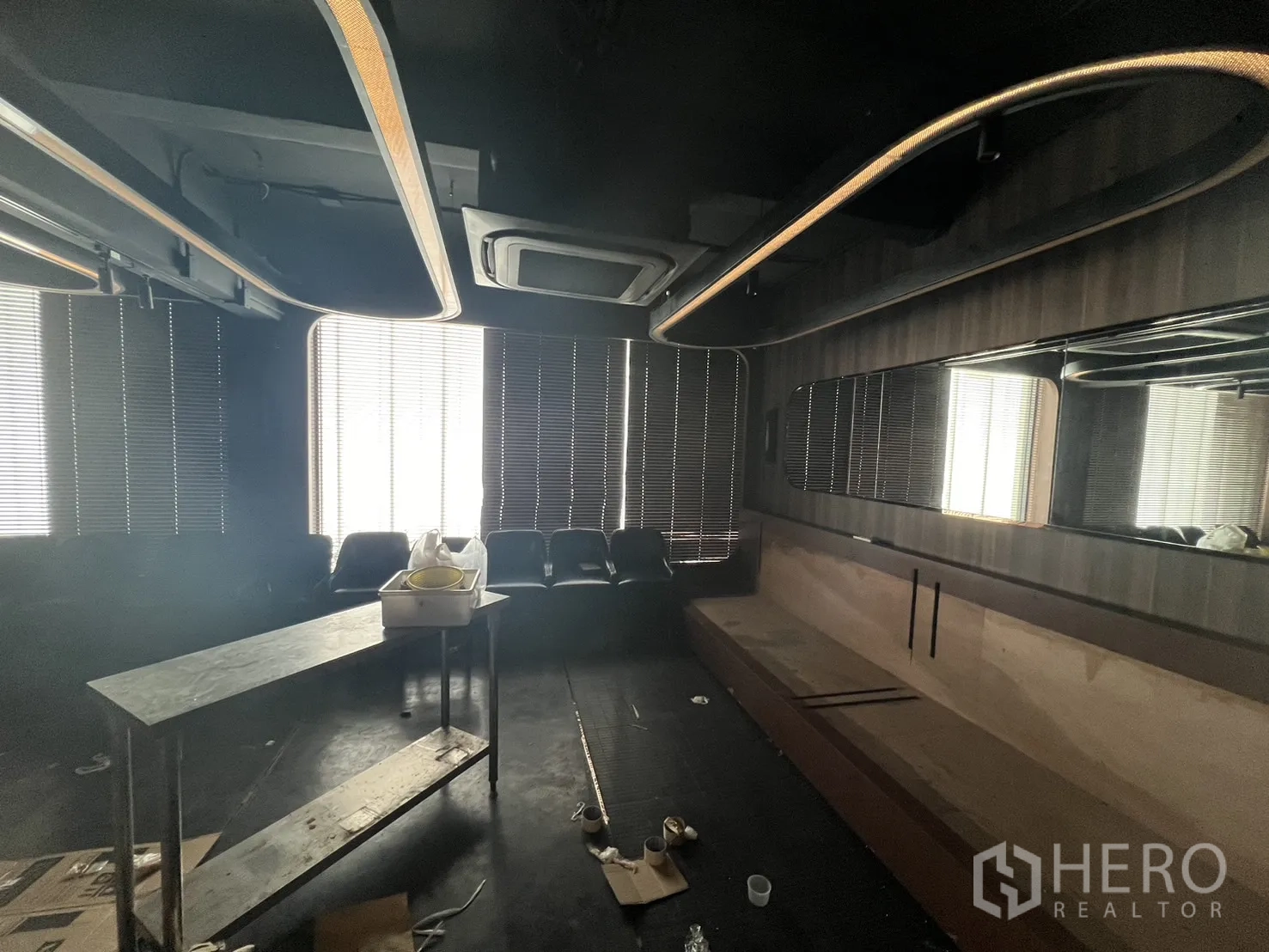 Shophouse for rent in Watthana, Bangkok - Dark lounge with blinds, oval ceiling light loops and long banquette seating.