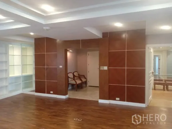 Condominium for rent in Khlong Toei, Bangkok - Spacious open-plan area with wood panel feature walls and recessed lighting.