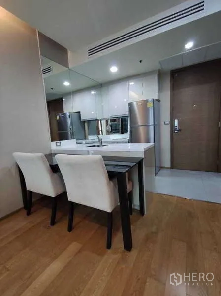 Condominium for rent in Bang Rak, Bangkok - Dining nook with two upholstered chairs next to the kitchen.