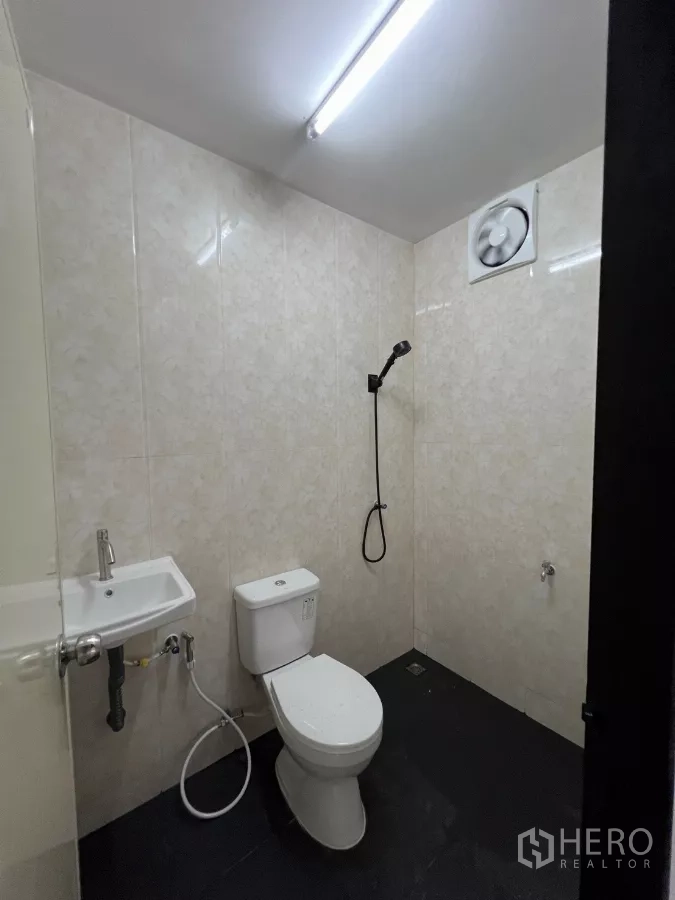 Warehouse for rent in Lam Luk Ka, Pathum Thani - Clean restroom with toilet, hand shower, sink and exhaust fan inside the facility.
