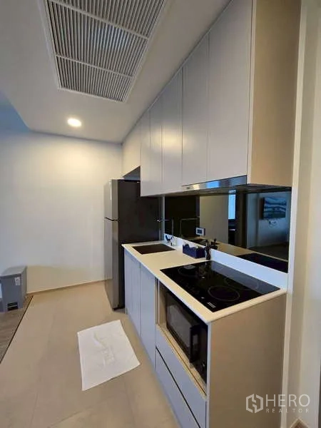公寓 出租在Phaya Thai, Bangkok - 走廊式厨房，利落柜体、电炉、微波炉与镜面挡板。