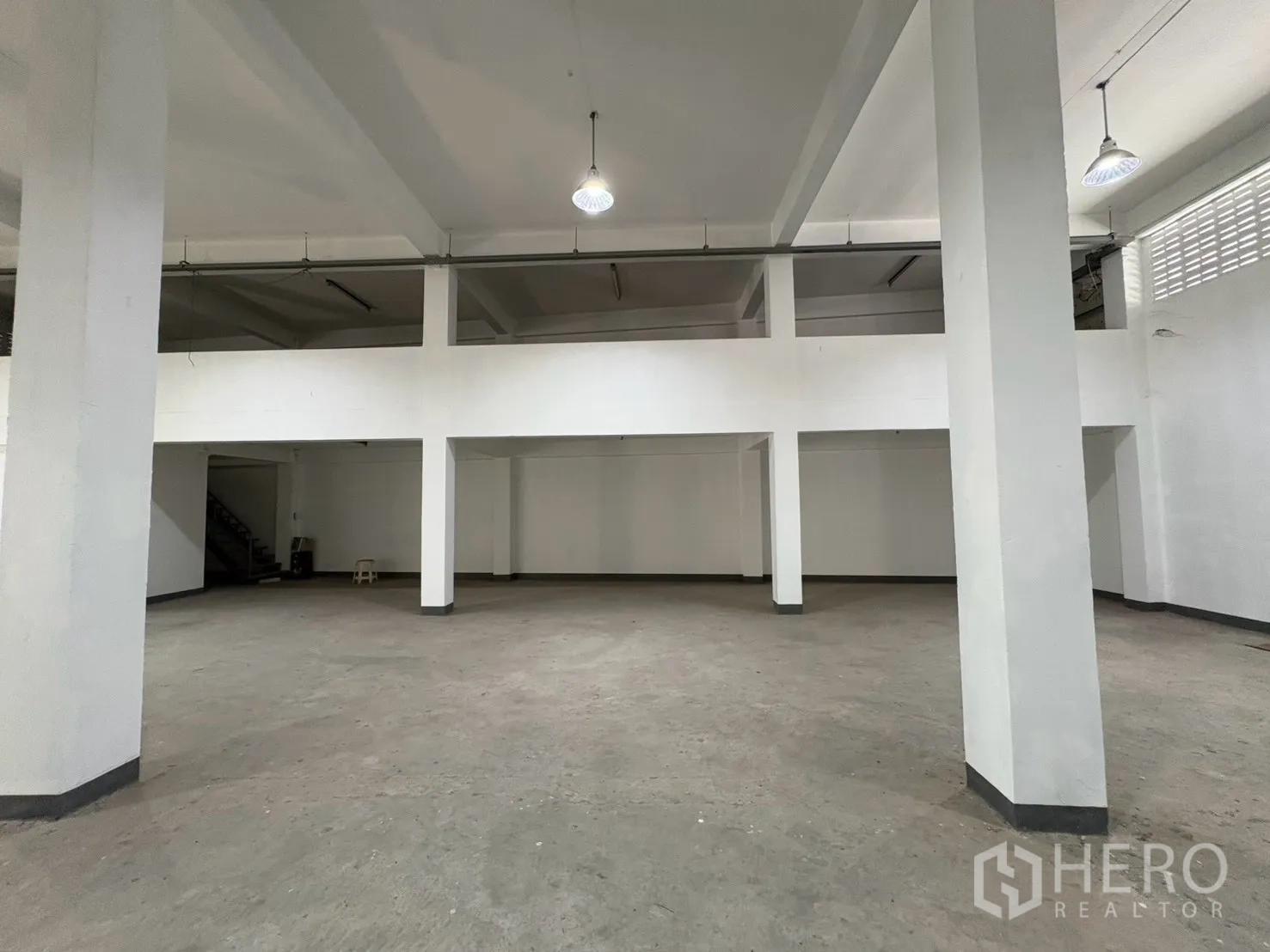 Warehouse for rent in Bang Na, Bangkok - Empty warehouse bay with columns and a mezzanine ledge above.