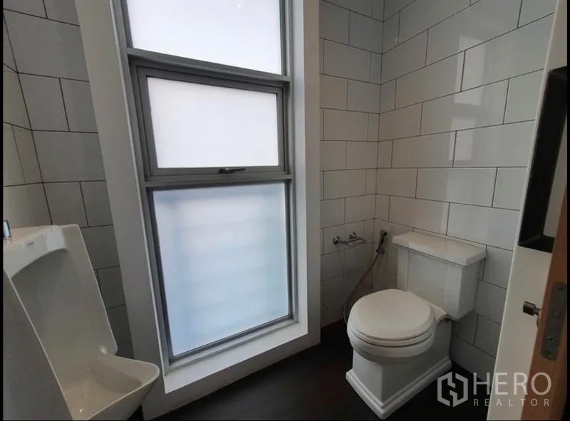 Condominium for rent in Watthana, Bangkok - Bright powder room with tiled walls, frosted window, toilet and urinal.