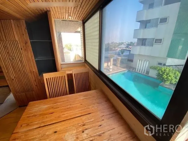 Condominium for rent or sale in Suan Luang, Bangkok - Corner dining nook by a large window overlooking the condominium swimming pool and city views.