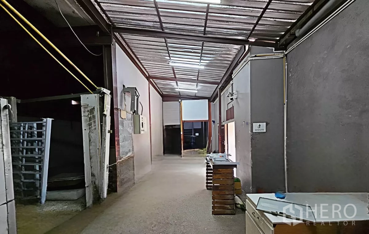 Warehouse for rent in Chatuchak, Bangkok - Central corridor with high metal roof, skylights and electrical panels.