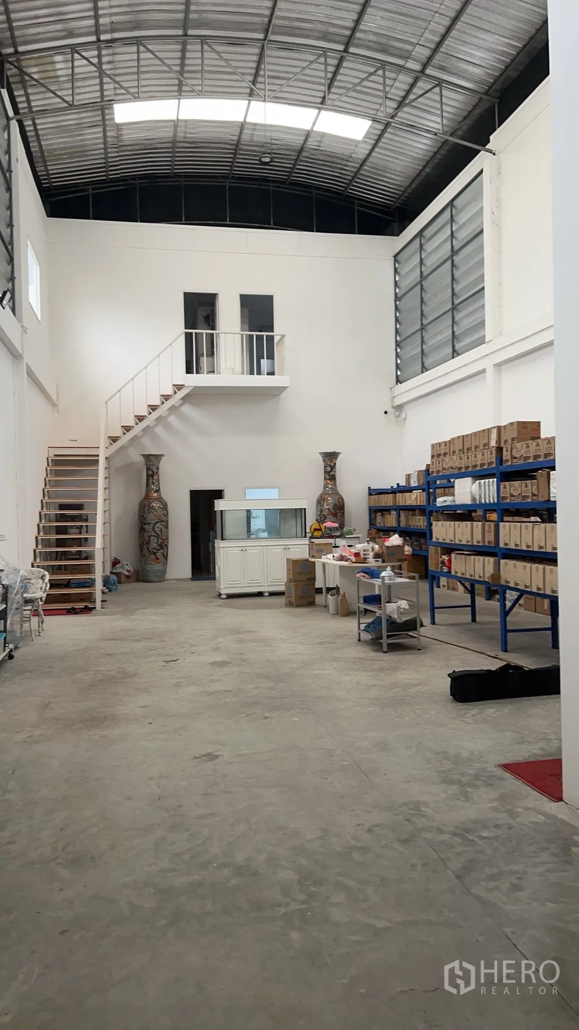 仓库 for sale in Lat Lum Kaeo, Pathum Thani - 仓库内部挑高空间，拱形钢屋顶，设有夹层与蓝色货架。