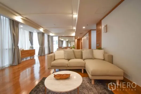 Condominium for rent in Pathum Wan, Bangkok - Bright living room with L‑shaped sofa, marble coffee table and floor‑to‑ceiling windows.
