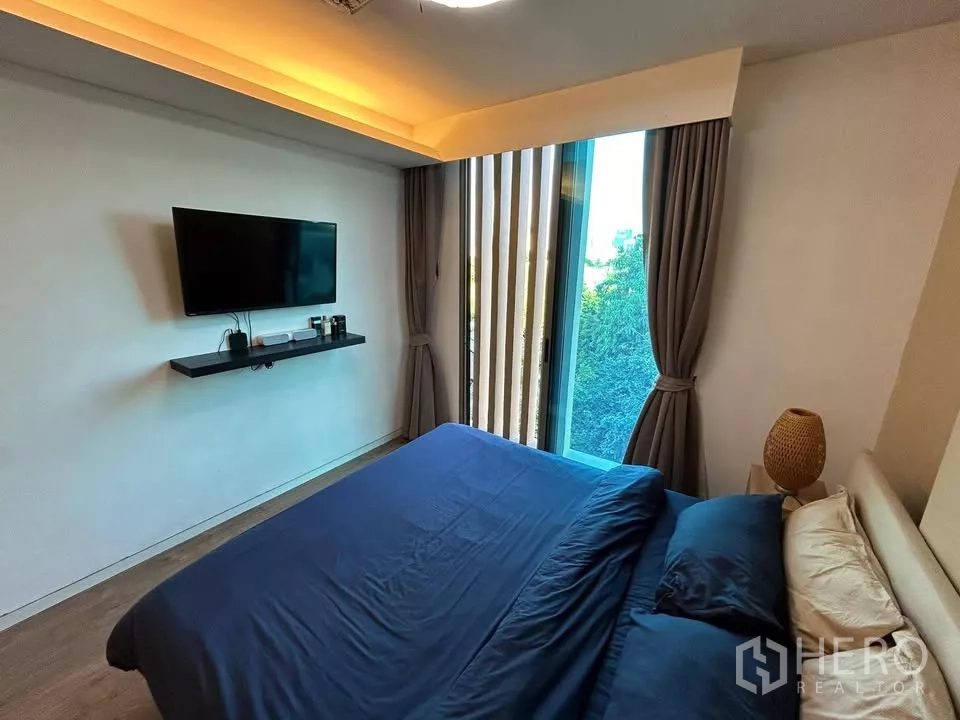 公寓 出租在Watthana, Bangkok - 主卧带落地窗，墙挂电视与窗帘，灯光柔和