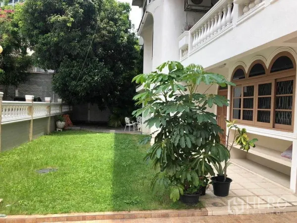 Detached House for rent in Watthana, Bangkok - Green front lawn beside the house with mature tree and arched windows along the facade.