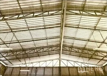 Warehouse for rent in Lat Phrao, Bangkok - Close-up of the gabled metal roof and steel truss structure inside the warehouse.