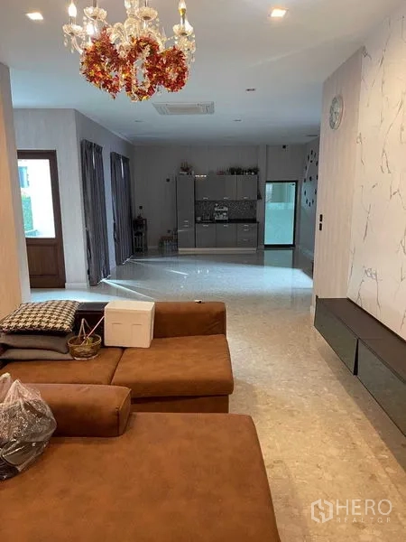 独立式住宅 出售在Mueang Samut Prakan, Samut Prakan - 开放式客厅，棕色转角沙发、吊灯，可见茶水吧与落地玻璃门