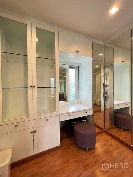 Detached House for sale in Bang Kruai, Nonthaburi - Bright dressing area with built‑in glass cabinets, a vanity desk, and mirrored wardrobes.