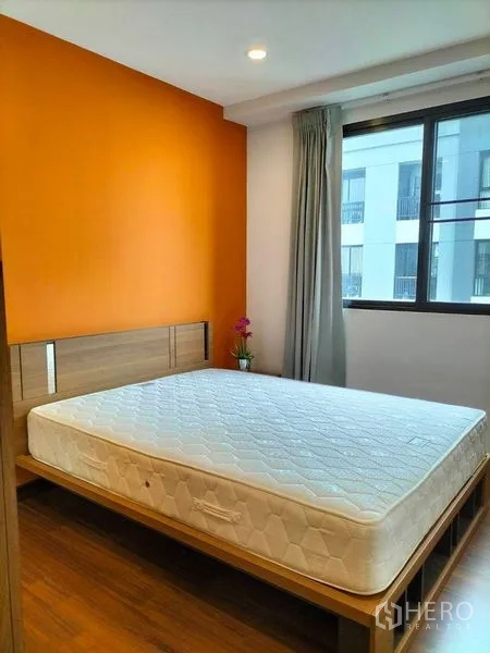 Condominium for rent in Watthana, Bangkok - Bright bedroom with orange accent wall, large window and queen bed.