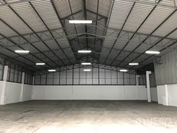 货栈 出租在Pak Kret, Nonthaburi - 仓库内部空间开阔，挑高钢结构屋顶与混凝土地面。