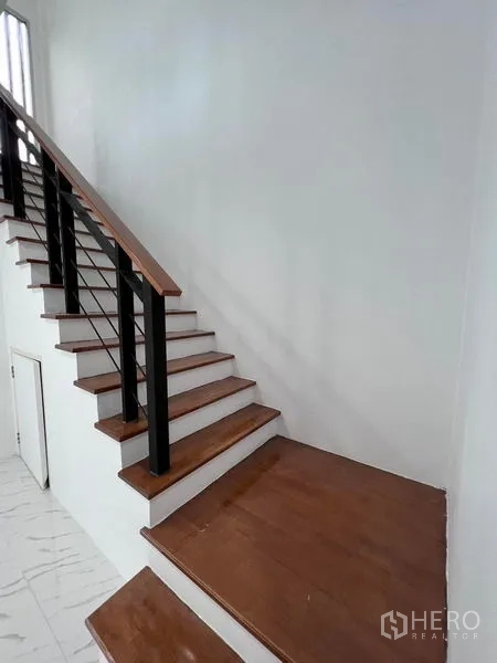 Home Office for sale in Lat Krabang, Bangkok - Close-up of L-shaped stair landing with wood steps and metal balustrade.