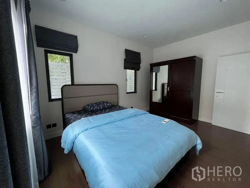 Detached House for rent in Bang Kapi, Bangkok - Cozy bedroom with blue bedding, dark wardrobe and twin windows