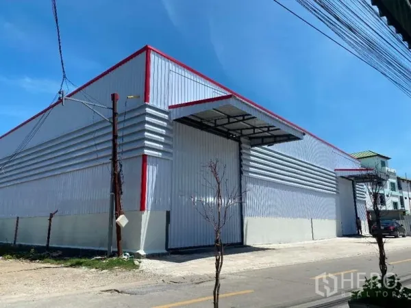 货栈 出租在Don Mueang, Bangkok - 屋顶红色线条点缀的仓库外立面，入口上方设遮雨装卸棚。